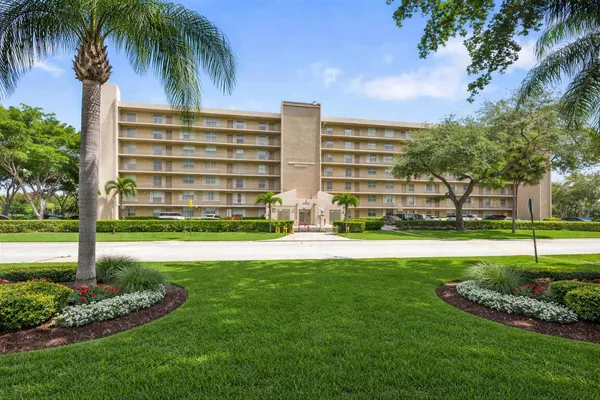 a view of a apartment with a big yard and palm trees