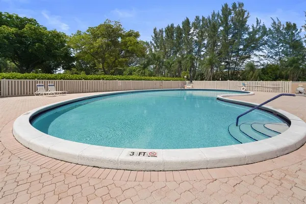 a view of a swimming pool with a yard and trees in the background