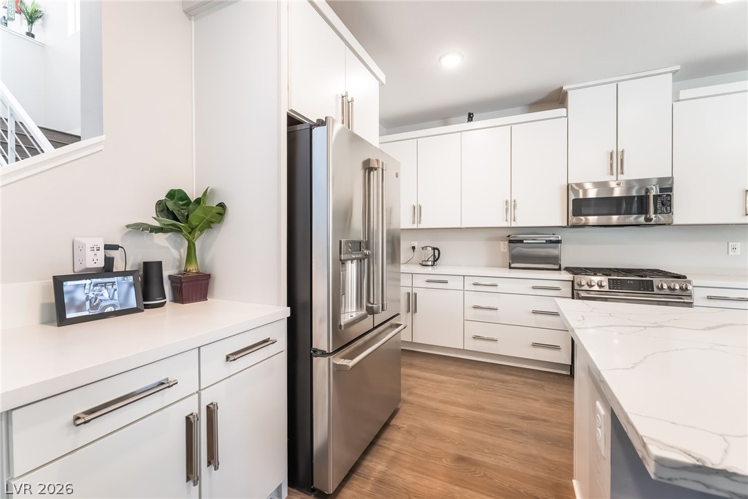 2166 Trivero Street Henderson, NV 89044 - Photo 15 of 61 A well-appointed culinary space featuring sleek white cabinetry and warm wood flooring.