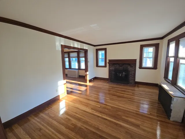 a view of empty room with wooden floor and fireplace