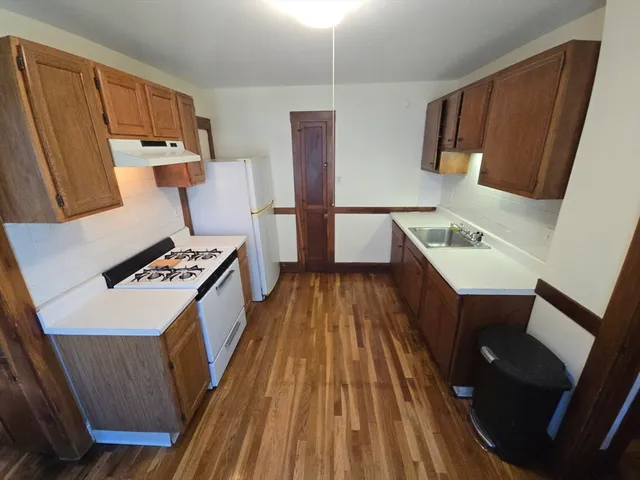 a kitchen with a sink a refrigerator a stove a microwave oven and a dining table with wooden floor