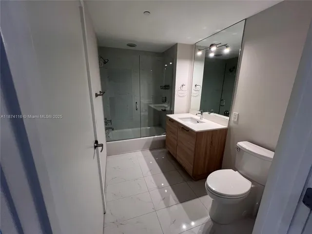 a view of an empty room with wooden floor and closet