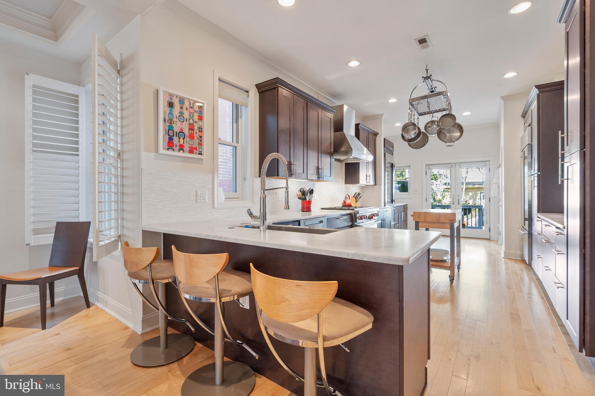33 W Street Northwest, Unit 1 Washington, DC 20001 - Photo 12 of 36 a large kitchen with stainless steel appliances kitchen island granite countertop a table chairs in it and wooden floors