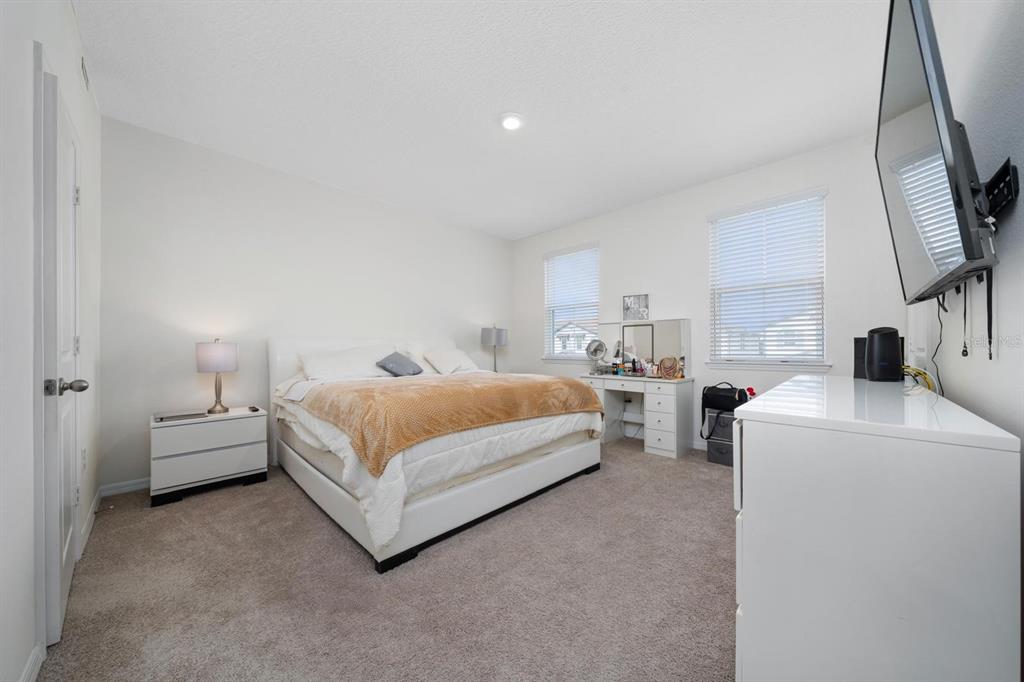 4450 Small Creek Road Kissimmee, FL 34744 - Photo 13 of 25 a bedroom with a bed and a flat tv screen on the dresser