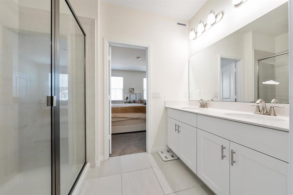 4450 Small Creek Road Kissimmee, FL 34744 - Photo 16 of 25 a en suite bathroom with a double vanity sink a mirror and shower