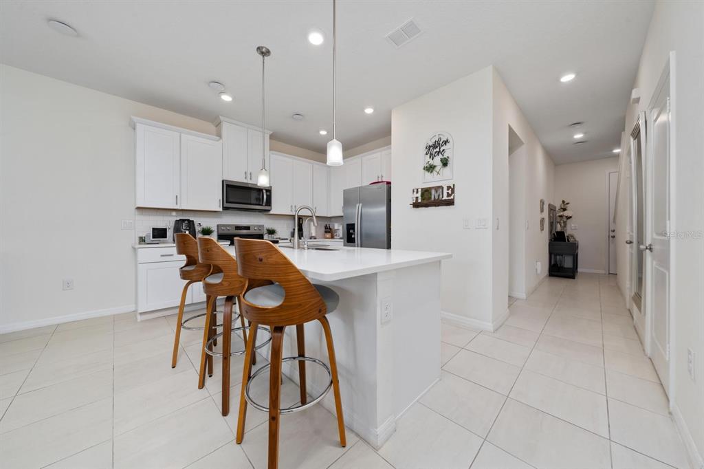 4450 Small Creek Road Kissimmee, FL 34744 - Photo 6 of 25 a kitchen with stainless steel appliances kitchen island granite countertop a refrigerator and microwave