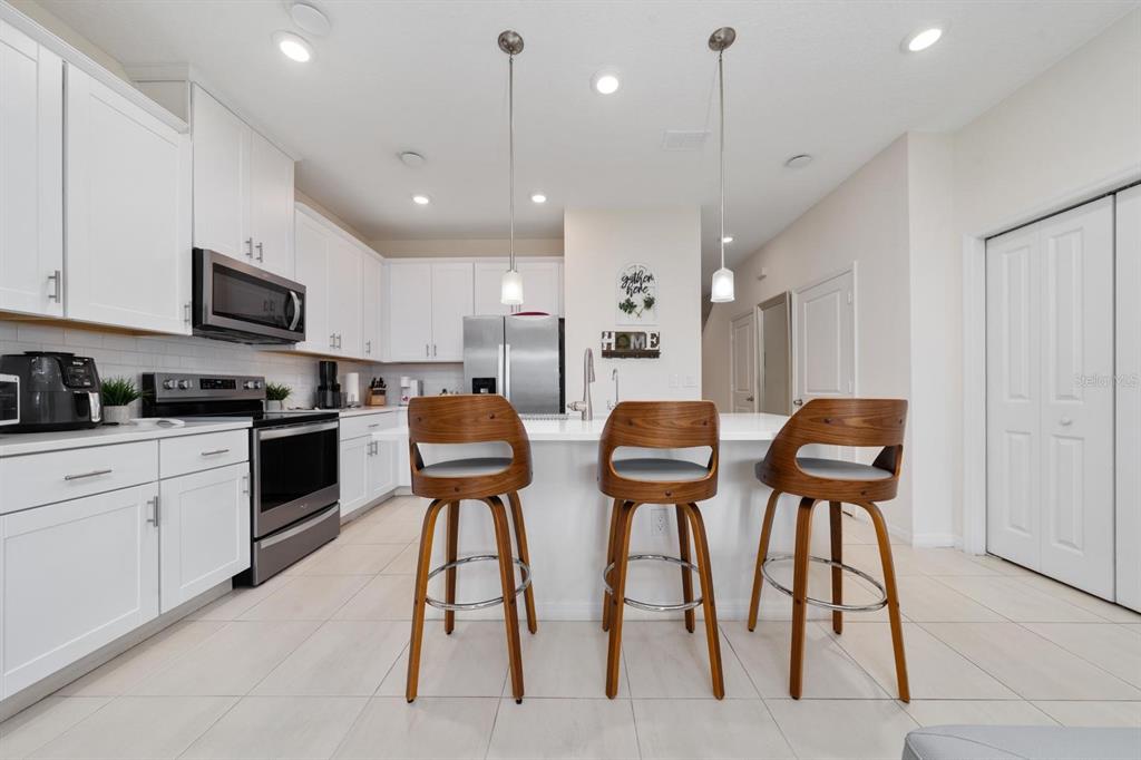 4450 Small Creek Road Kissimmee, FL 34744 - Photo 8 of 25 a kitchen with stainless steel appliances kitchen island granite countertop a stove a sink a refrigerator and chairs