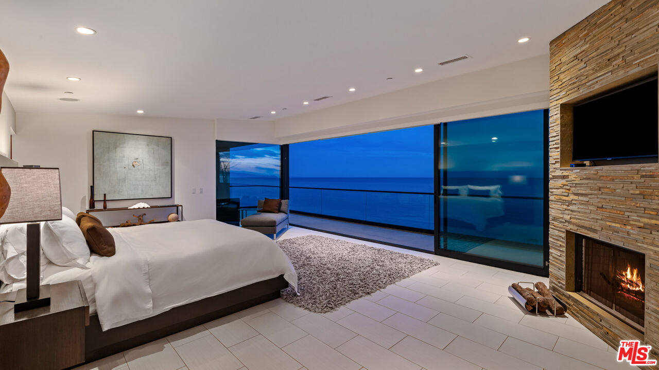 25250 Malibu Road Malibu, CA 90265 - Photo 61 of 69 a bedroom with a bed and a fireplace