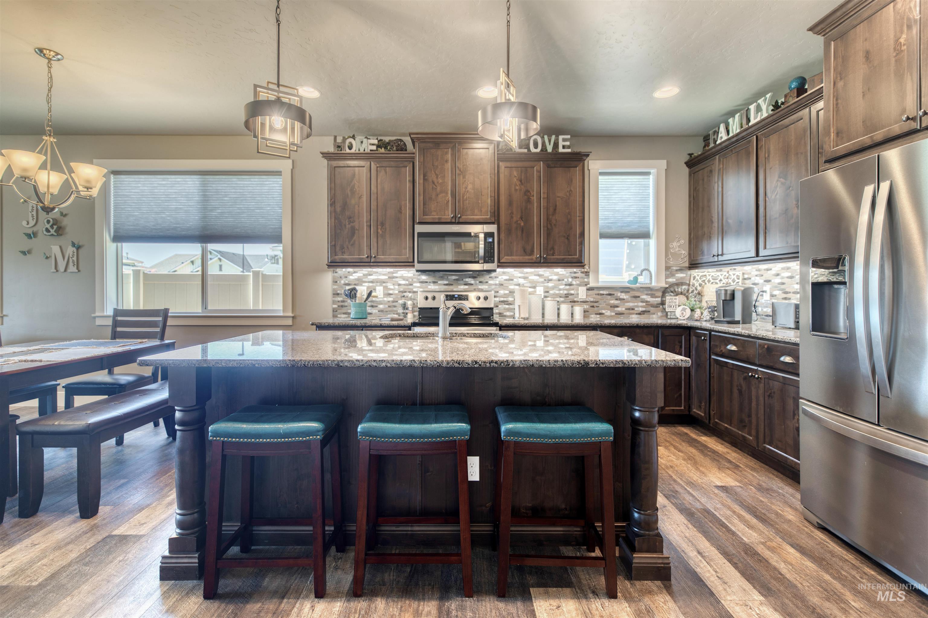 11913 West Piazza Street Nampa, ID 83686 - Photo 9 of 50 Kitchen with stainless steel appliances, dark brown cabinets, light stone countertops, and decorative backsplash