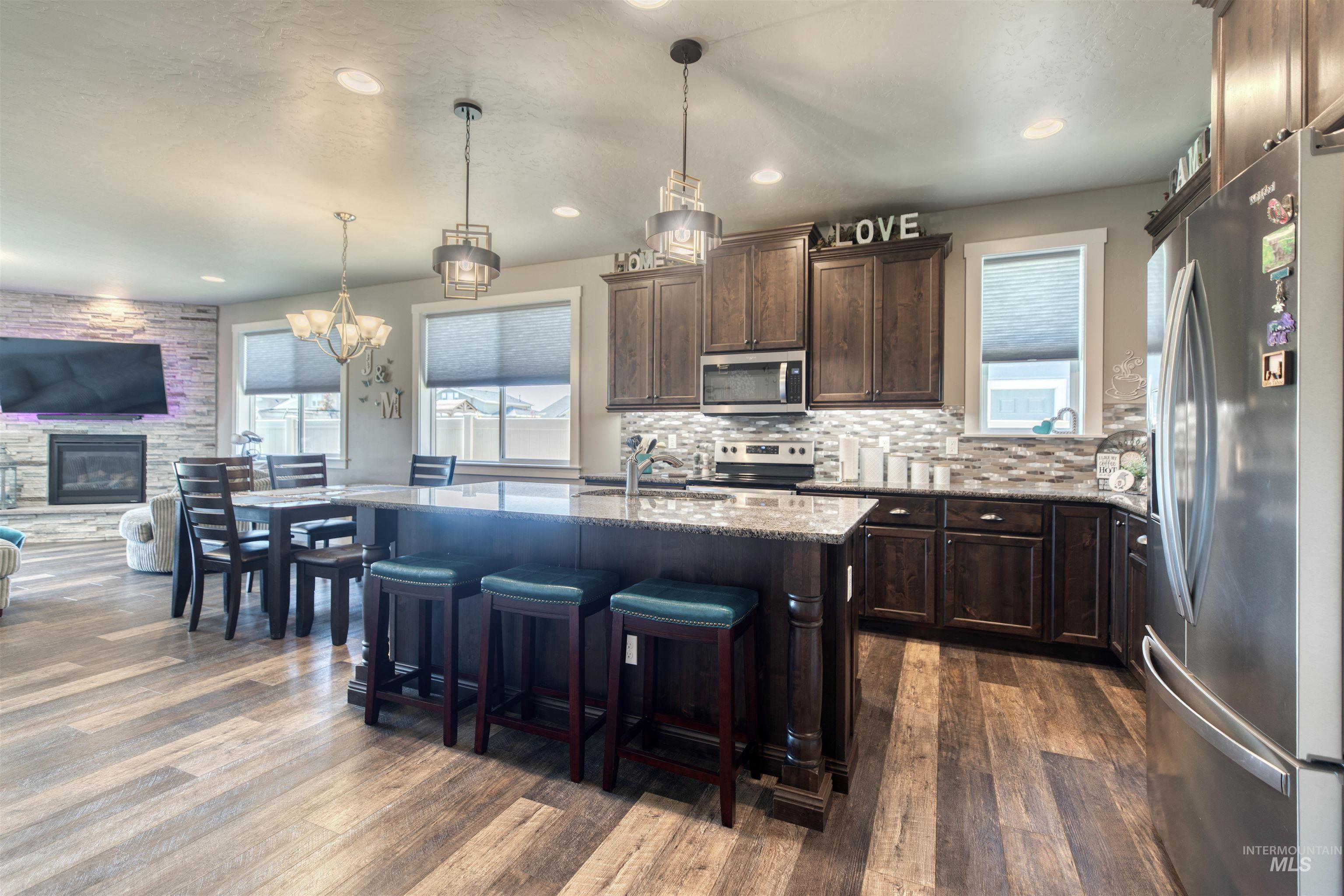 11913 West Piazza Street Nampa, ID 83686 - Photo 49 of 50 Kitchen featuring stainless steel appliances, light stone countertops, open floor plan, hanging light fixtures, and recessed lighting