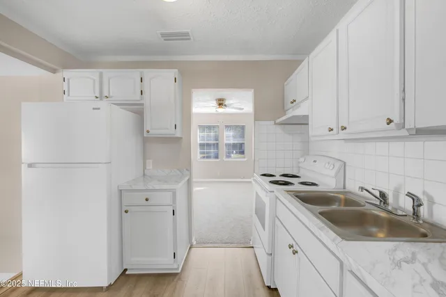 a kitchen with white cabinets and white appliances