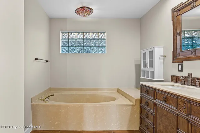 a bathroom with a tub a sink and a window