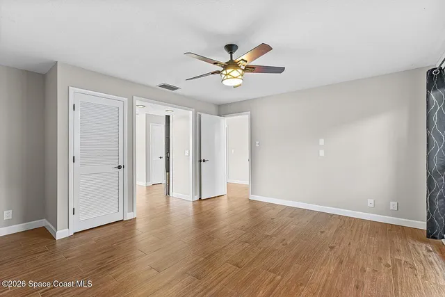 a view of an empty room with window and wooden floor