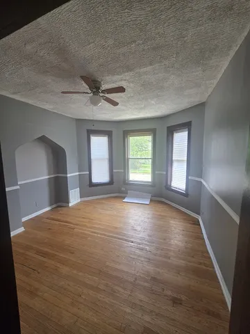 a view of empty room with wooden floor and fan