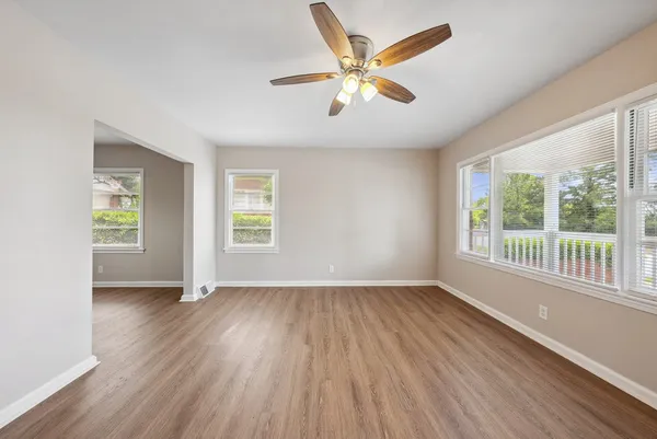 a view of an empty room with wooden floor and a window