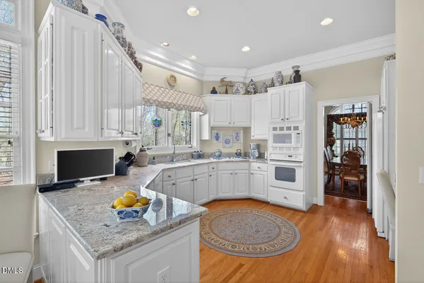 a kitchen with stainless steel appliances granite countertop a sink dishwasher and a stove with wooden floors