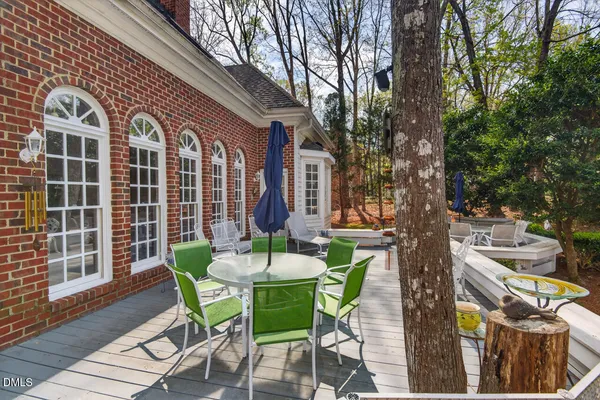 a view of a patio with a dining table and chairs with wooden floor and fence