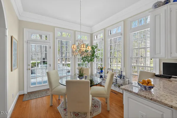 a dining room with wooden floor a flat screen tv and a floor to ceiling window