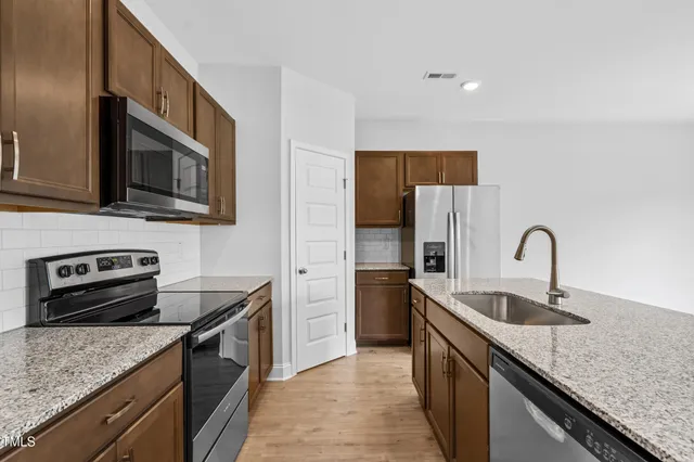 a kitchen with stainless steel appliances granite countertop a sink stove and refrigerator