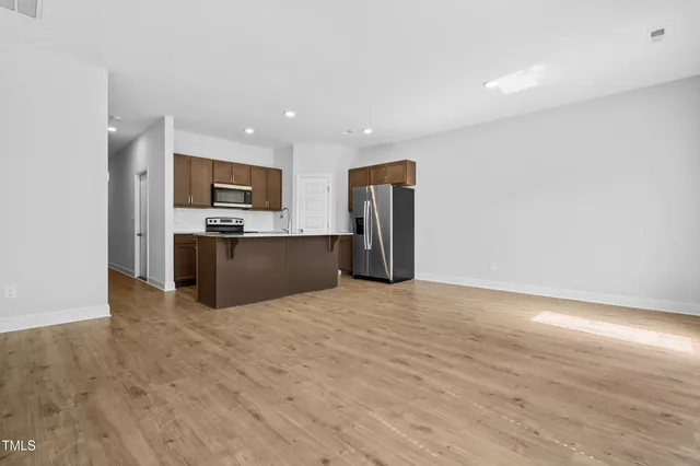 a view of kitchen with stainless steel appliances wooden floor and living room