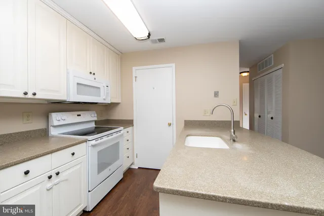 a kitchen with granite countertop white cabinets and white appliances