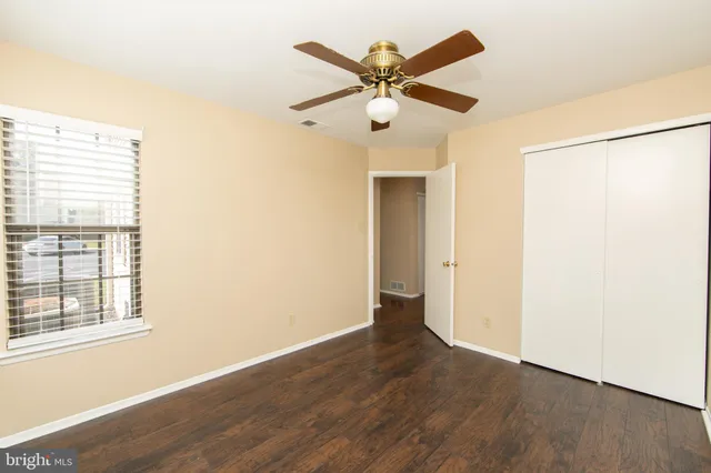 an empty room with wooden floor fan and windows