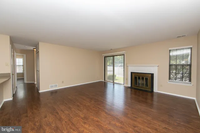 an empty room with wooden floor fireplace and windows