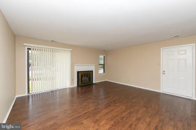 an empty room with wooden floor fireplace and windows
