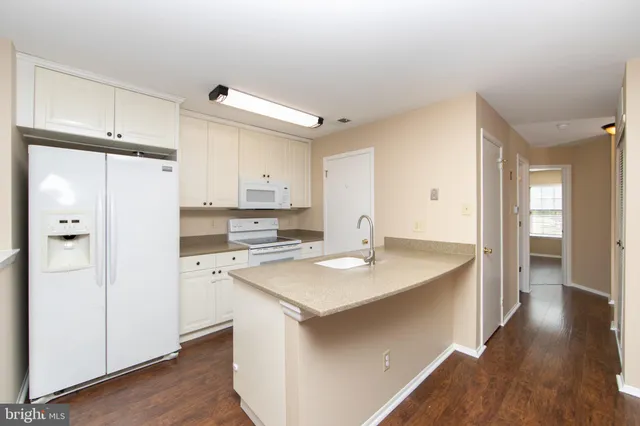 a kitchen with a sink a stove cabinets and wooden floor