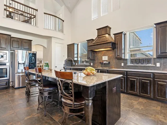 a kitchen with stainless steel appliances granite countertop a stove top oven a sink a dining table and chairs