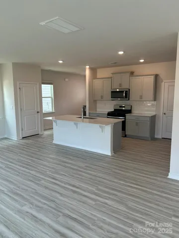 a large kitchen with stainless steel appliances a large counter top a stove a sink and a refrigerator