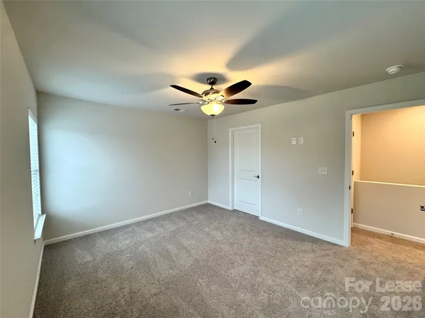 an empty room with ceiling fan and window