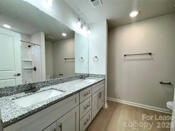 a bathroom with a granite countertop sink a mirror and a toilet