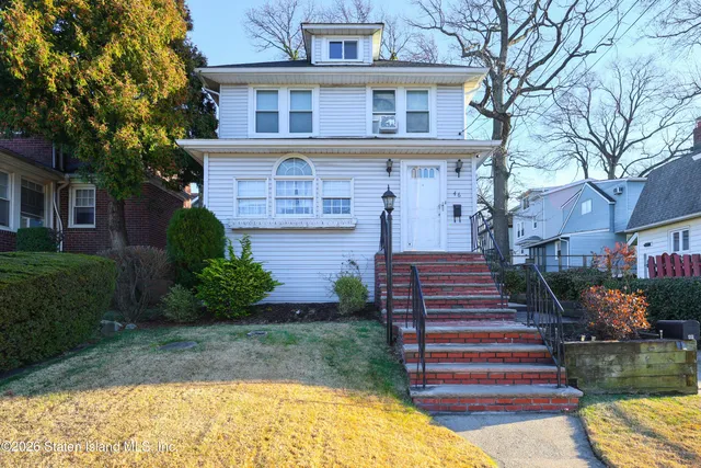 a front view of a house with a yard and potted plants