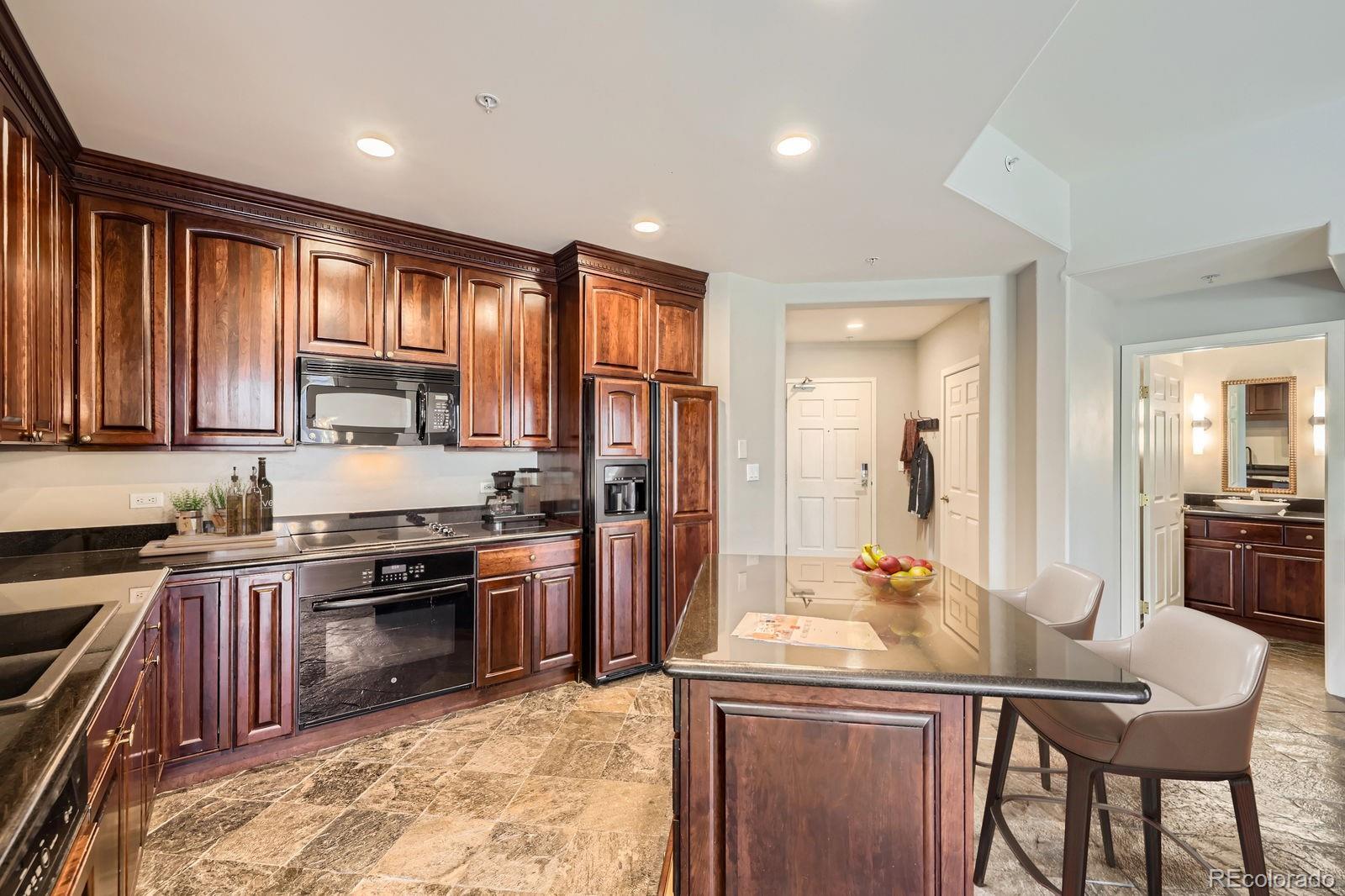 4875 South Monaco Street, Unit 103 Denver, CO 80237 - Photo 7 of 44 a kitchen with stainless steel appliances granite countertop a stove top oven a sink dishwasher a dining table and chairs with wooden floor