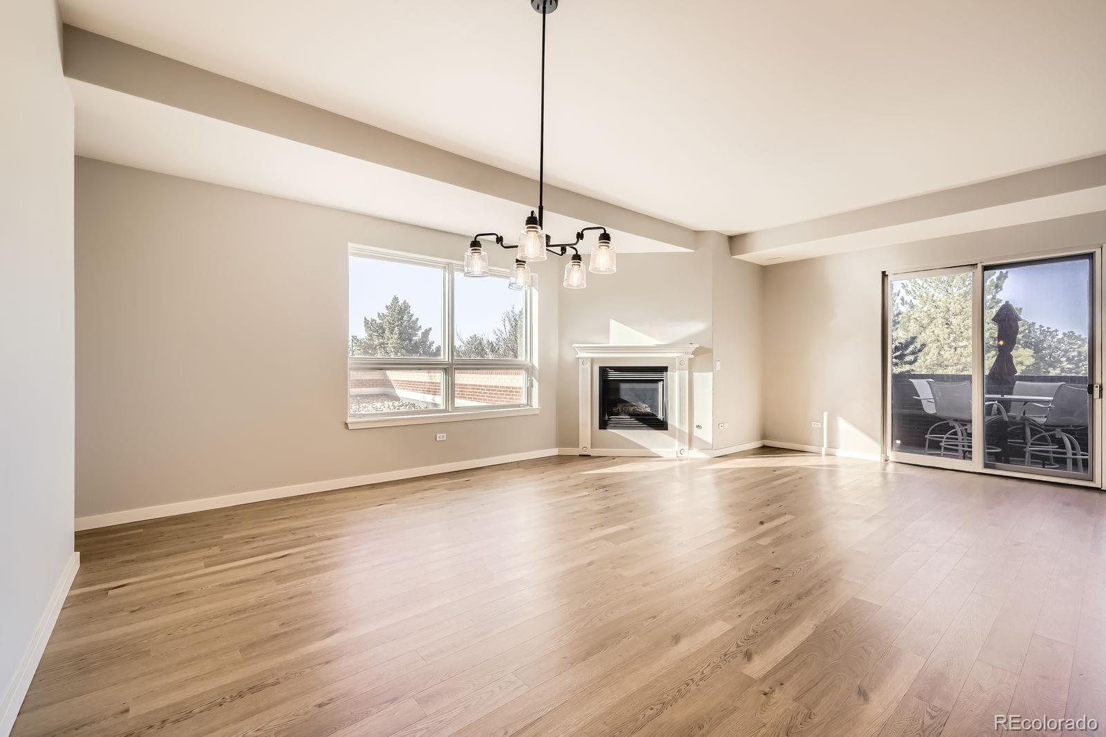 4875 South Monaco Street, Unit 103 Denver, CO 80237 - Photo 10 of 44 a view of a livingroom with wooden floor a fireplace and windows