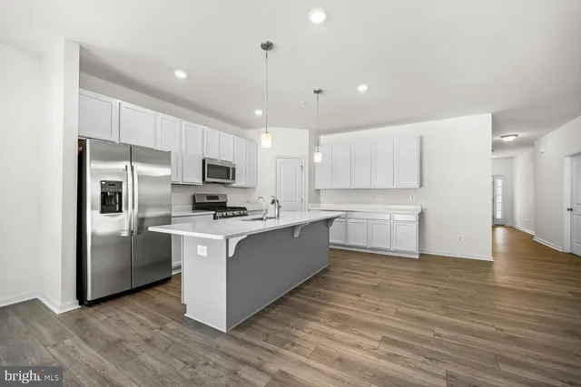 a large kitchen with stainless steel appliances granite countertop a stove top oven a refrigerator a sink and a microwave