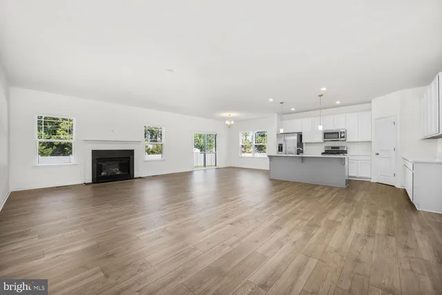 a view of kitchen and hall with wooden floor and a fireplace