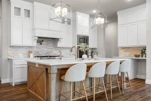 a kitchen with cabinets a sink dishwasher a stove and a dining table with wooden floor