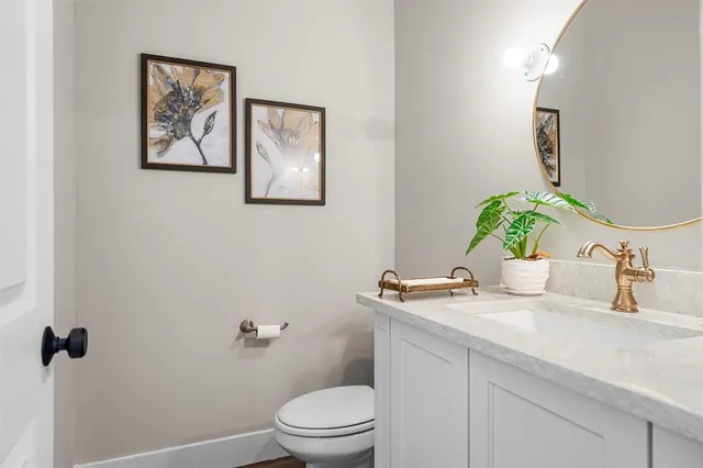a bathroom with a granite countertop sink a toilet and mirror