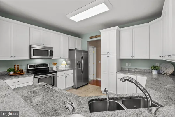 a kitchen with granite countertop a stove sink and microwave
