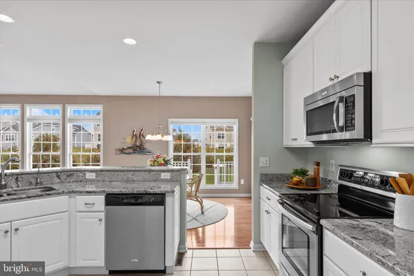 a kitchen with granite countertop white cabinets and white stainless steel appliances with a window