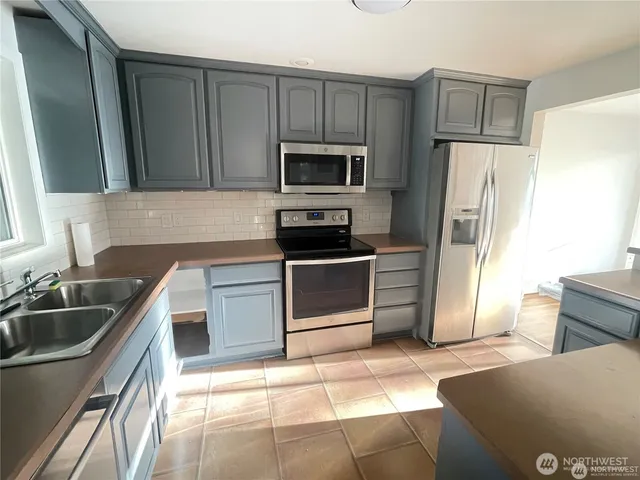 a kitchen with stainless steel appliances granite countertop a refrigerator sink and stove