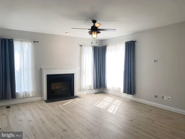 an empty room with windows fireplace and a kitchen view