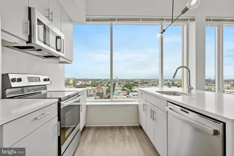 a kitchen with a sink cabinets stainless steel appliances and a window
