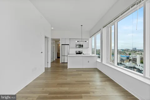 a large white kitchen with kitchen island a large window appliances and cabinets