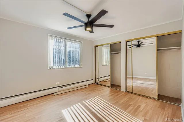 a view of empty room with wooden floor and fan