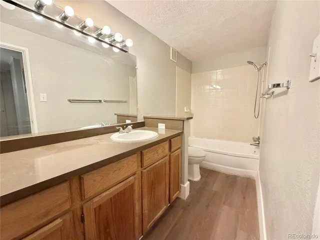 a spacious bathroom with a granite countertop sink a toilet mirror and shower