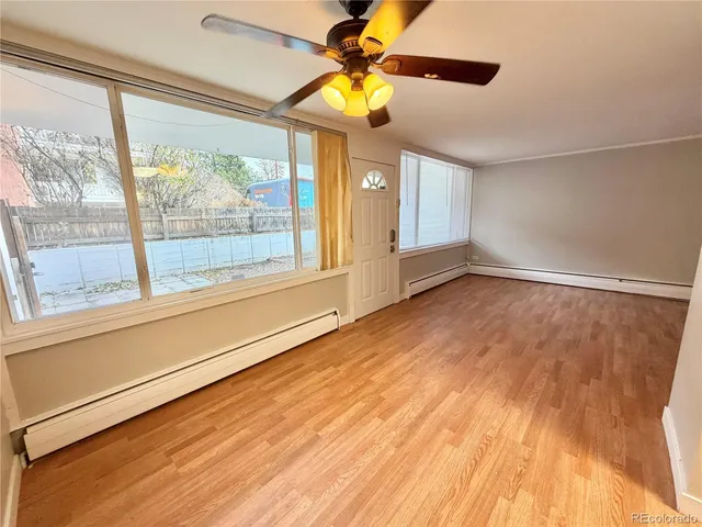 a view of an empty room with a window and wooden floor