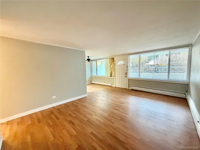 an empty room with wooden floor and windows